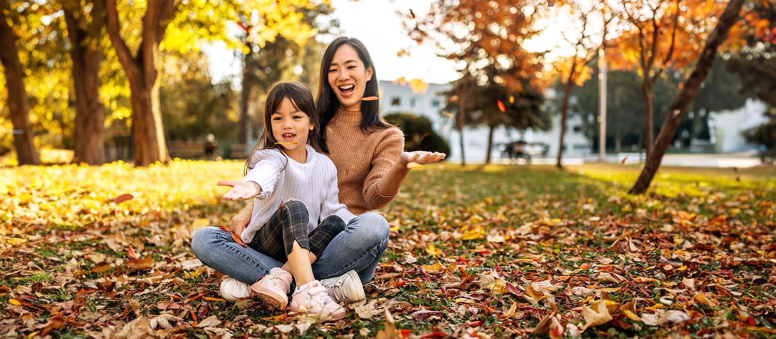 Mother and daughter enjoying autumn leaves